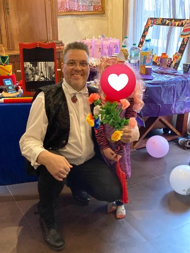Rigadin accroupi à côté d’une petite fille qui tient un bouquet de fleurs en ballons