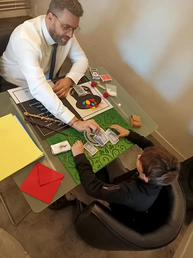 Vu d’en haut, Rigadin fait un tour de cartes à une table face à un jeune spectateur