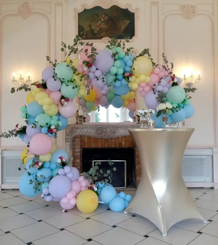 Arche de ballons pastel autour d’une cheminée, dans une salle de réception