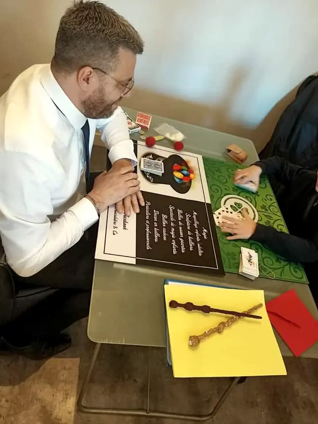 Rigadin montre un tour de cartes à un enfant, à une table de magie