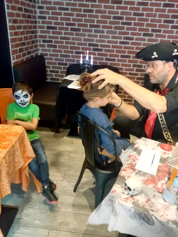 Rigadin en pirate maquille une fillette, à côté d’un garçon déjà grimé